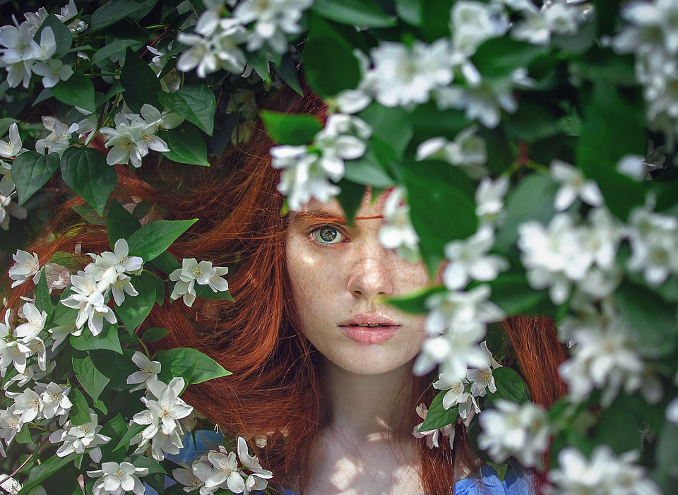 woman with beautiful skin behind spring branches
